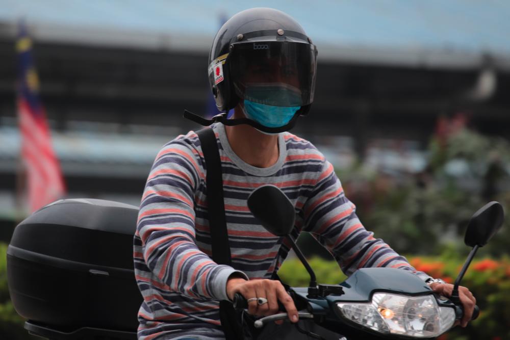 A motorcyclist wears mask as haze blankets Kuala Lumpur on Sept 18, 2019. - AFP