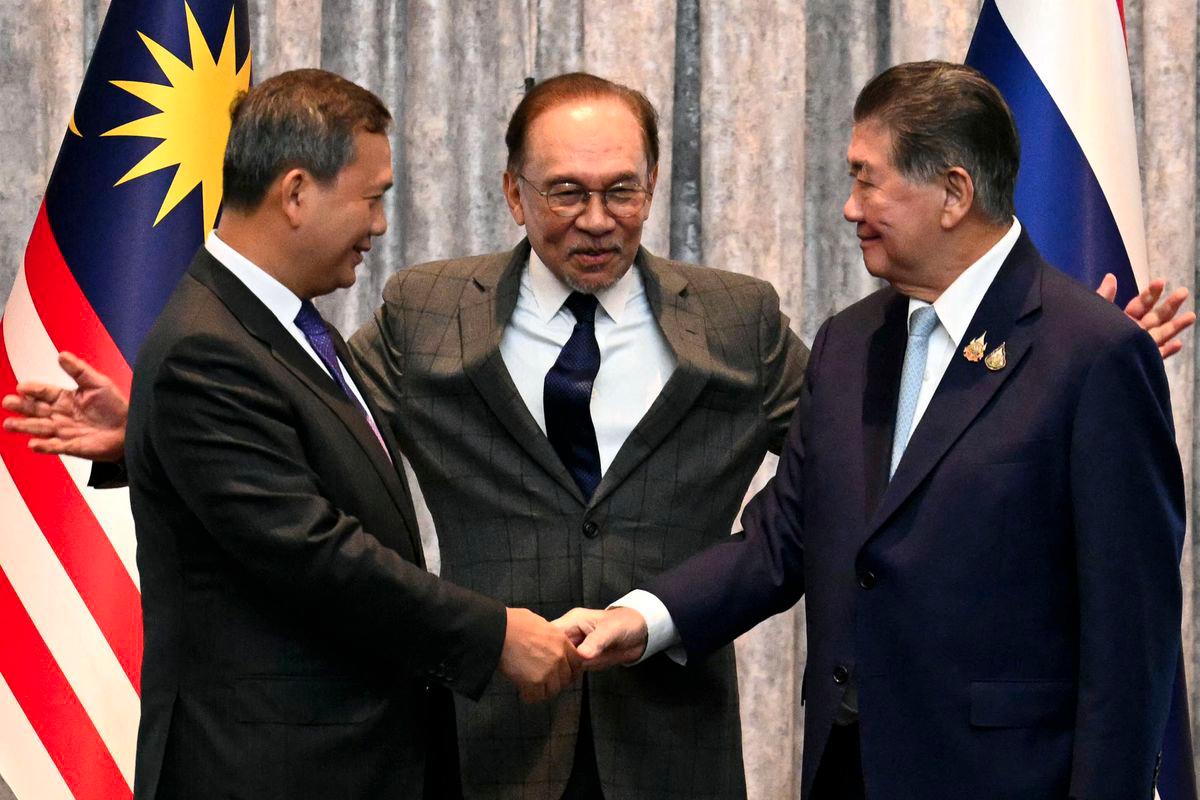 Cambodia's Prime Minister Hun Manet (L) and Thailand's acting Prime Minister Phumtham Wechayachai (R) shake hands as Malaysia's Prime Minister Anwar Ibrahim (C) puts his arms around them following a press conference after talks on a possible ceasefire between Thailand and Cambodia in Putrajaya on July 28, 2025. - AFPPIX