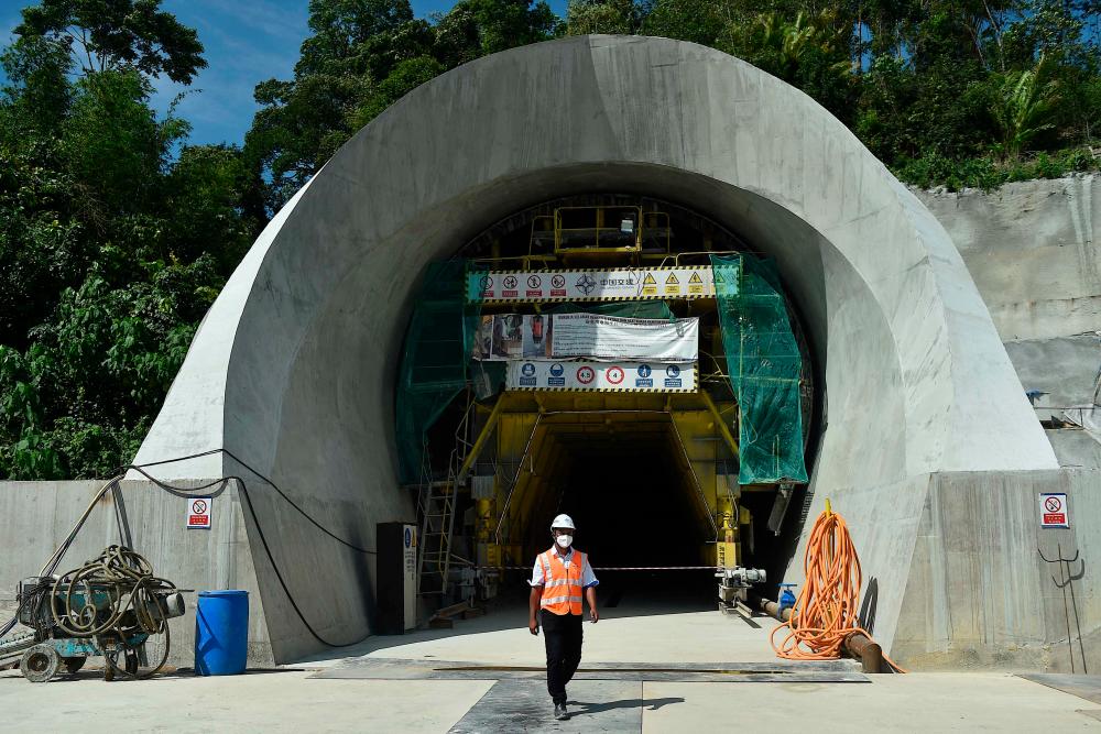 Seorang pekerja berjalan melepasi Terowong Genting, sebahagian daripada projek Laluan Rel Pantai Timur (ECRL), semasa lawatan tapak di Bentong di negeri Pahang Malaysia pada 13 Januari 2022. AFPPIX