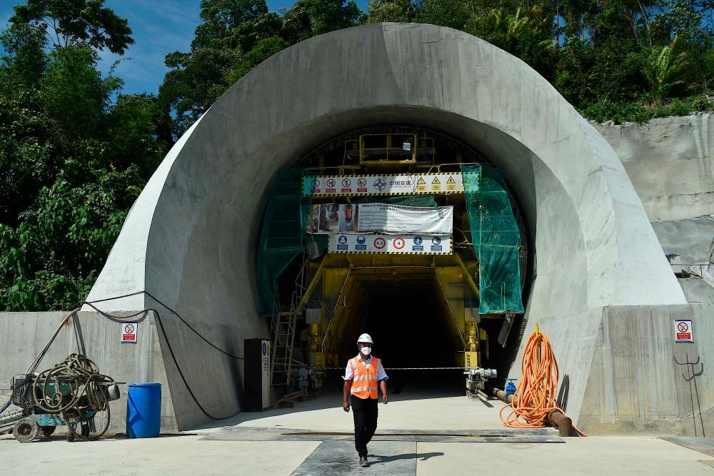 A worker walks past the Genting Tunnel, part of the East Coast Rail Link (ECRL) project, during a site visit in Bentong in Malaysia's Pahang state on January 13, 2022. AFPPIX
