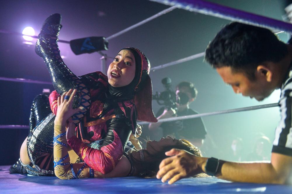 This picture taken on December 10, 2022 shows Malaysian hijab-wrestler Nor “Phoenix” Diana wrestling with Japan wrestler Yuki Kamifuku during a match organised by APAC Wrestling at Puchong in Selangor. Nor Diana is spearheading attempts to break down the gender barrier in the niche, male-dominated sport in Malaysia. AFPPIX