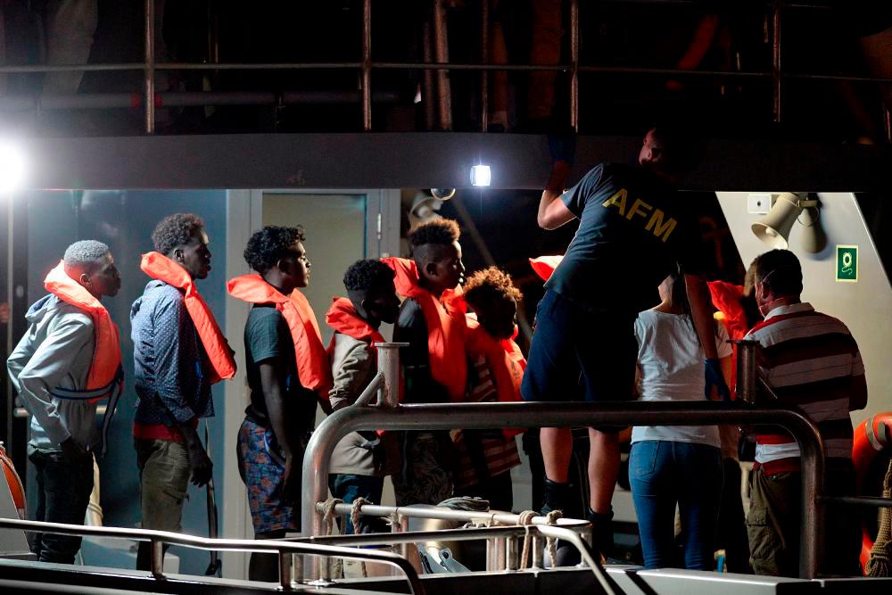 (FILES) Migrants, part of a group of 65 rescued by the German-flagged NGO rescue ship Alan Kurdi, queue as they are brought into Haywharf, in Valletta, by the Armed Forces of Malta after being transferred onto the Maltese patrol boat on July 7, 2019. AFPPIX