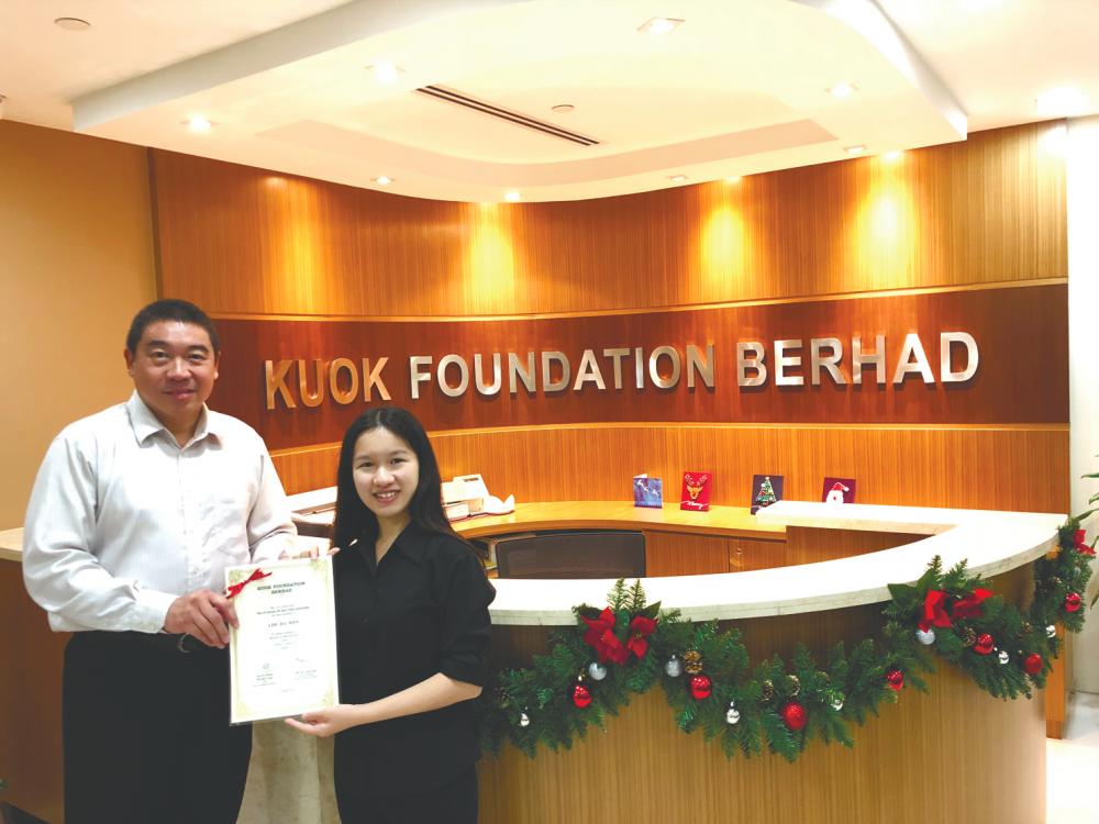 Kuok Foundation general manager Ng presents a scholarship to a recipient, Lim.