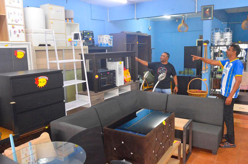 Radhi (right) at his shop in Seberang Jaya, where he sells second-hand goods such as furniture, beds, closets and electrical appliances. - MASRY CHE ANI/THESUN