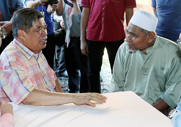 Minister of Defence Mohamad Sabu speaks with fallen firefighter Muhammad Adib’s father, Mohd Kassim Abdul Hamid, while visiting the family in Kampung Tebengau, Kuala Kedah. — BBXpress