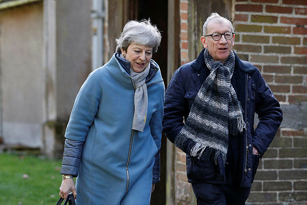 Britain’s Prime Minister Theresa May (L) leaves with her husband Philip (R) after attending a church service, near her Maidenhead constituency, west of London — AFP