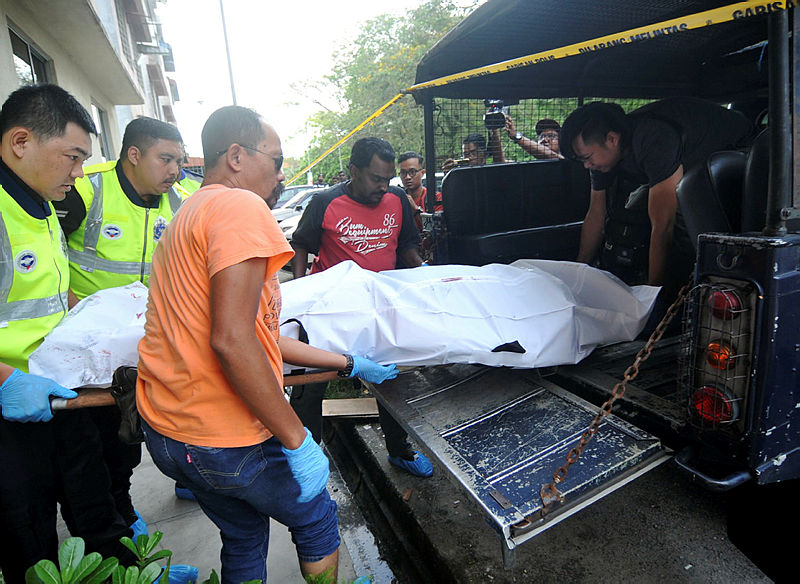 Police officers load the body of the victim into a van to be taken for a post-mortem. — Bernama