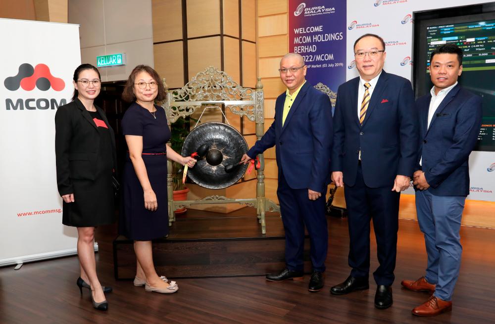 Executive director Chew Lee Poh (second from left) and Ho (centre) hitting the gong at the listing ceremony this morning.