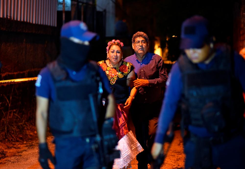 People react next to police officers guarding a crime scene where unidentified assailants opened fire at a bar in Minatitlan, in Veracruz state, Mexico, April 19, 2019. — Reuters