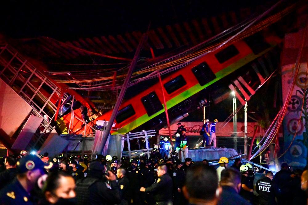 Rescue workers gather at the site of a metro train accident after an overpass for a metro partially collapsed in Mexico City on May 3, 2021. At least 13 people were killed and dozens injured in a metro train accident in the Mexican capital on May 3, the authorities said. –AFP