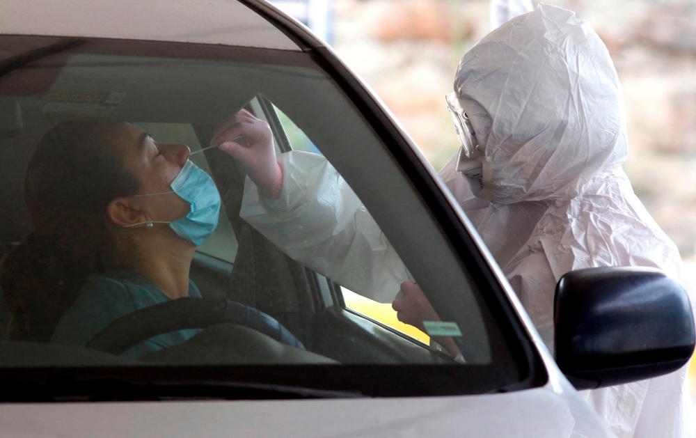 A health worker takes a swab sample from a driver to be tested for Covid-19, at the drive-thru test center of the Exact Sciences and Engineering University Center at the University of Guadalajara, in Guadalajara, Jalisco state, Mexico, on January 19, 2022. AFPpix