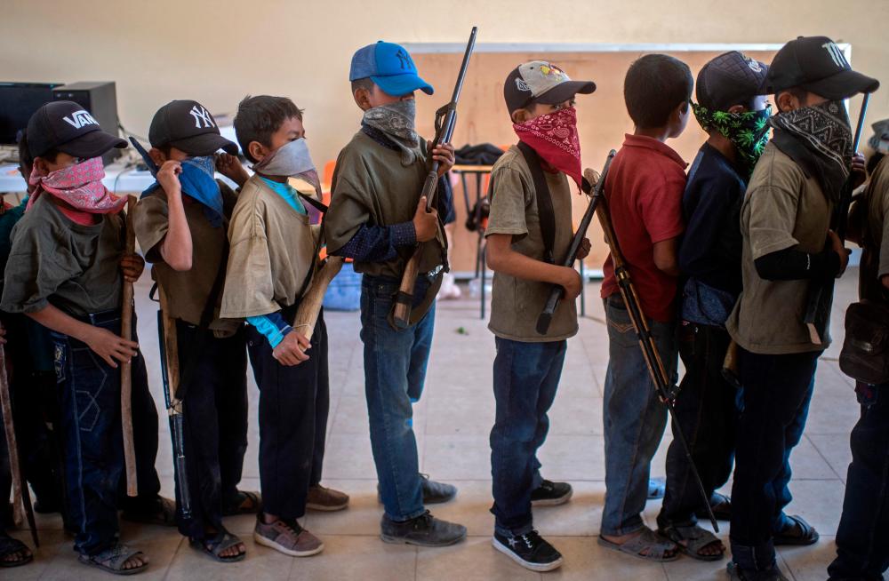 Children prepare to take part in a training demonstration of the Regional Coordinator of Community Authorities (CRAC-PF) vigilante force, in the village of Ayahualtempa, Guerrero State, Mexico, on April 10, 2021. –AFP