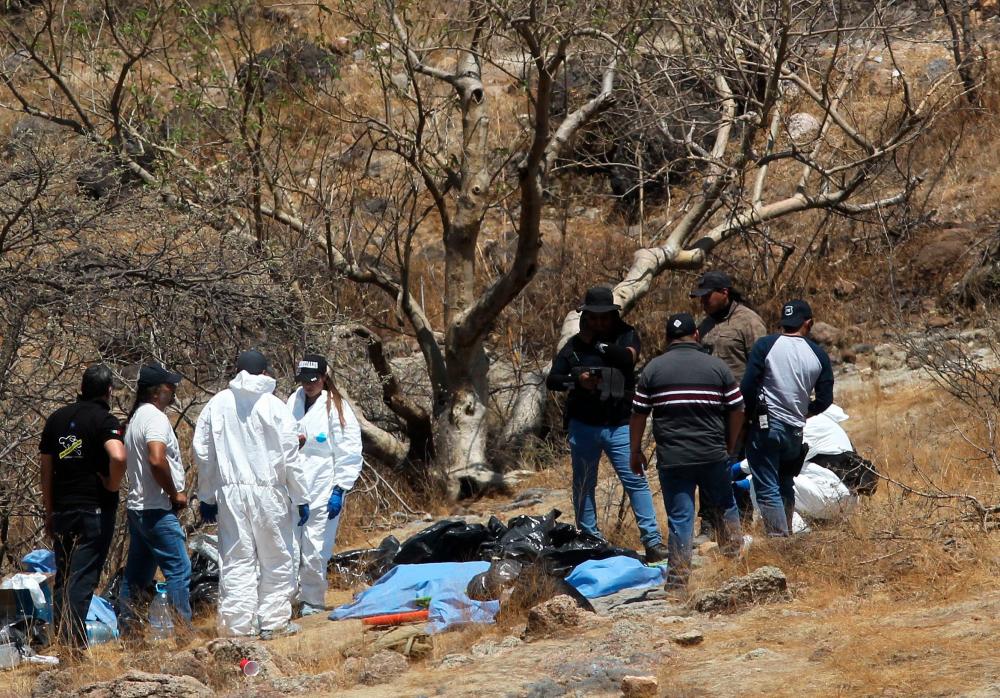 Forensic experts work with several bags of human remains extracted from the bottom of a ravine by a helicopter, which were abandoned at the Mirador Escondido community in Zapopan, Jalisco state, Mexico on May 31, 2023. AFPPIX