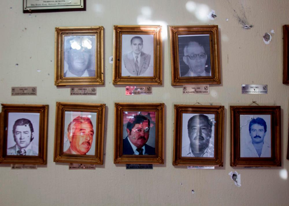 View of the bullet impacts in photographs of former Municipal Presidents with bullet impacts inside the Municipal Presidency in Villa Union, Coahuila state, Mexico, on Dec 2, 2019. — AFP
