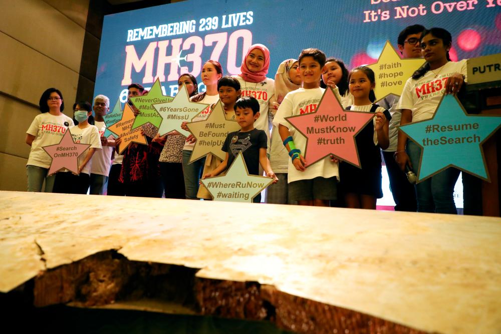 Family members of the victims pose for a group picture with a debris of the missing Malaysia Airlines flight MH370 during its sixth annual remembrance event in Putrajaya, Malaysia, March 7, 2020. — Reuters