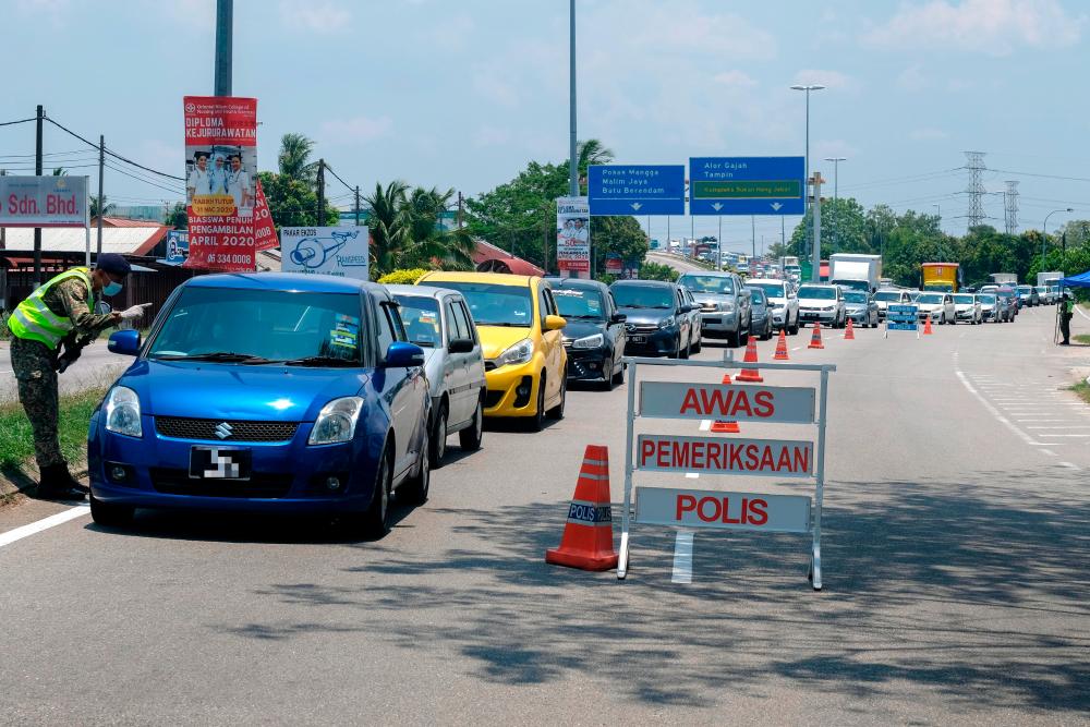 A member of the Malaysian Armed Forces (ATM) inspects the vehicle in a roadblock following the second phase of the Movement Control Order (MCO) at the AMJ Expressway yesterday. - Bernama