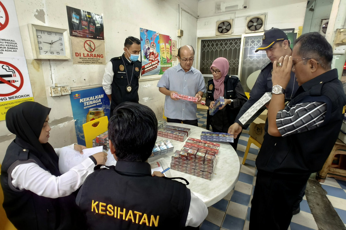 Melaka State Executive Councillor for Health, Human Resources, and Unity, Datuk Ngwe Hee Sem (fourth from right), and State Health Director, Dr Ruzita Mustaffa (third from right), inspect cigarettes believed to be counterfeit or smuggled, sold at prices below RM12, during the “Operasi Selamat Paru-Paru” late last night. – BERNAMA