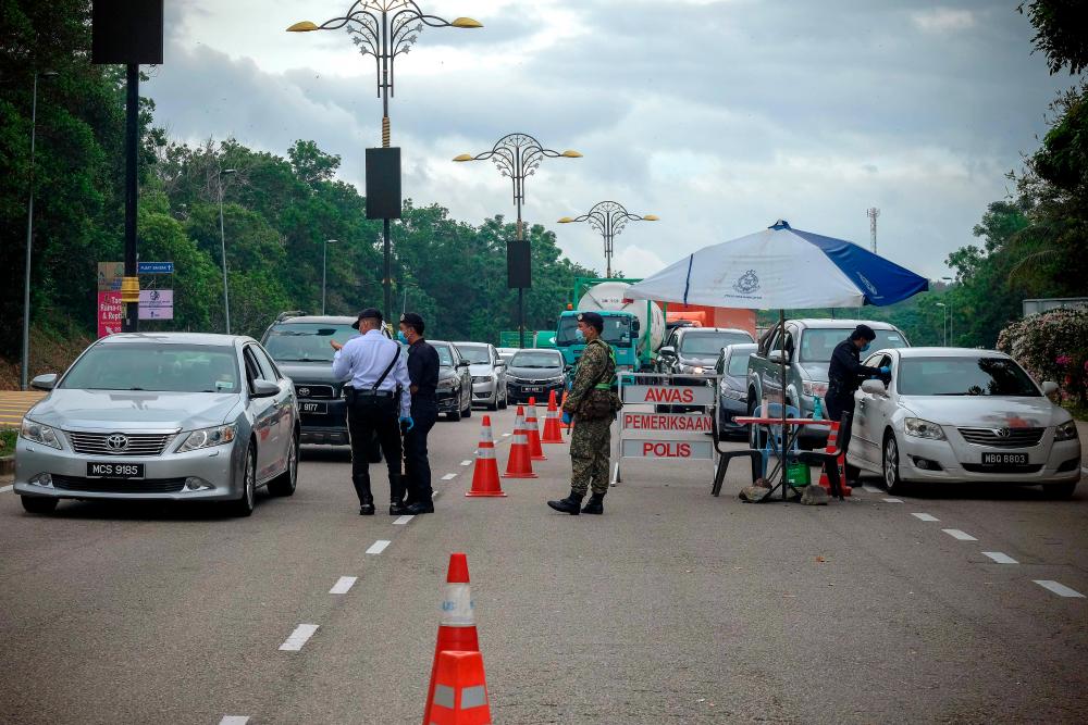 Police and military personnel conduct a road block at the Ayer Keroh toll plaza today. - Bernama