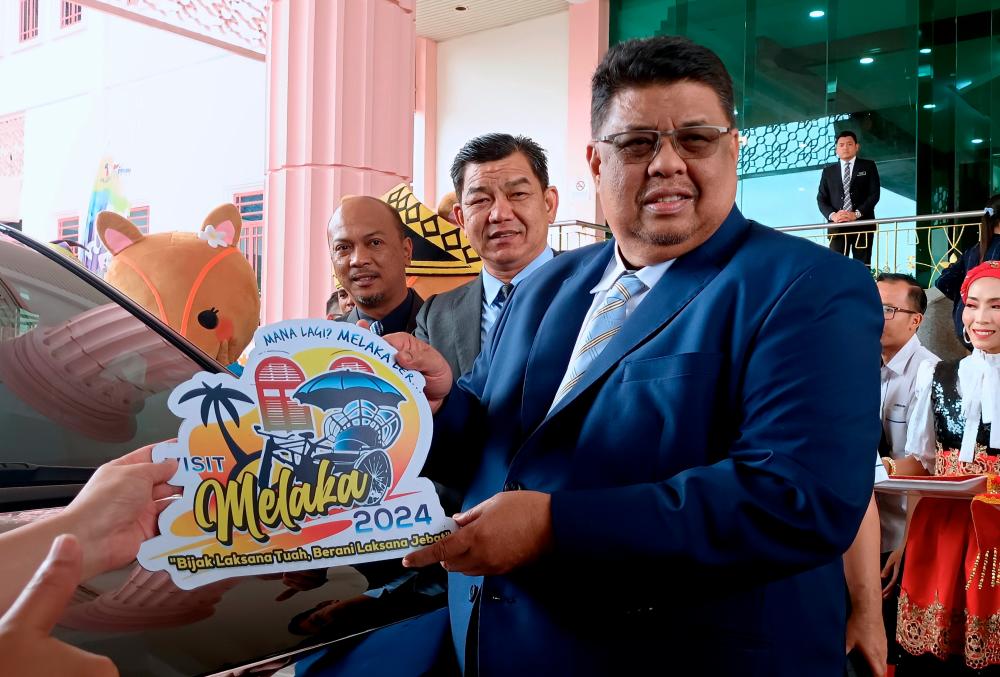 MALACCA, 16 August -- Malacca Chief Minister Datuk Seri Ab Rauf Yusoh (right) shows the promotional stickers for the Year of Visiting Melaka 2024 (TMM 2024) after officiating the TMM2024 Promotional Vehicle Sticker Handover Ceremony at Kompleks Seri Negeri here today. BERNAMAPIX