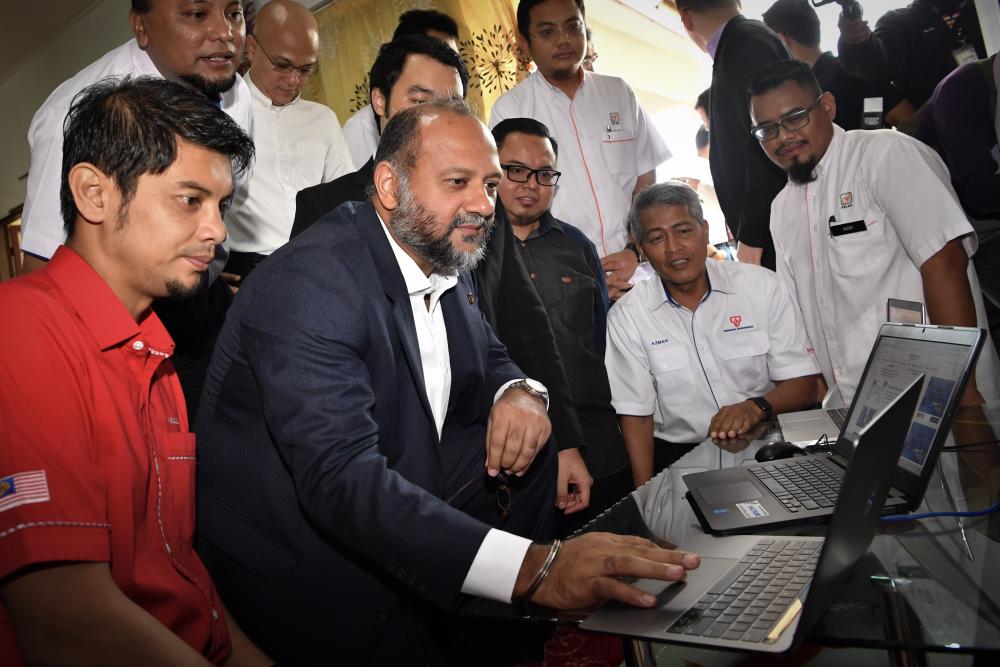 Communications and Multimedia Minister Gobind Singh Deo (2L) checks the internet facility available during a visit to the National Fiberisation and Connectivity Plan (NFCP) pilot project at Felda Tun Ghafar Kemendor, on Jan 8, 2018. — Bernama