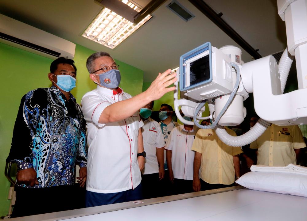 Health Minister Datuk Seri Adham Baba (2nd from L) looks closely at the digital X-ray machine after witnessing the handover of the health clinic construction project in Batu Berendam, Malacca today. - Bernama