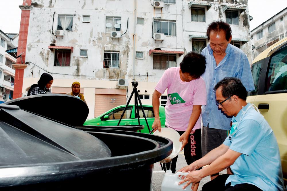 Kota Laksamana assemblyman Low Chee Leong (R), assists residents of an apartment in the area to store water from a tank, on Sept 15, 2019. — Bernama
