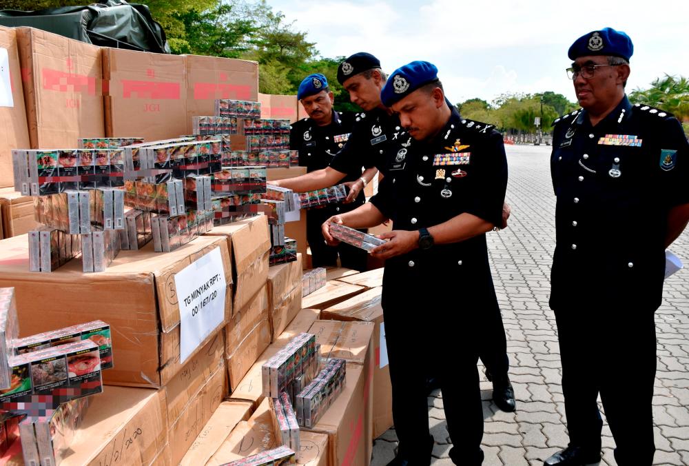 Bukit Aman Marine Police commander SAC Mohd Yusoff Mamat (2nd from R) inspects smuggled cigarettes seized during a special operation at a press conference at the Customs, Immigration, and Quarantine Complex in Malacca today. - Bernama