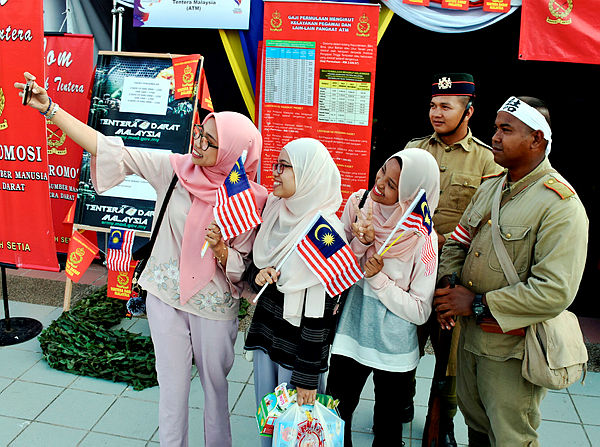 Three sisters take a selfie with two military personnel in the uniforms of the Malay Regiment and the Japanese Imperial Army during the British colonial era, at the National Month expo on Aug 3, 2019. — Bernama