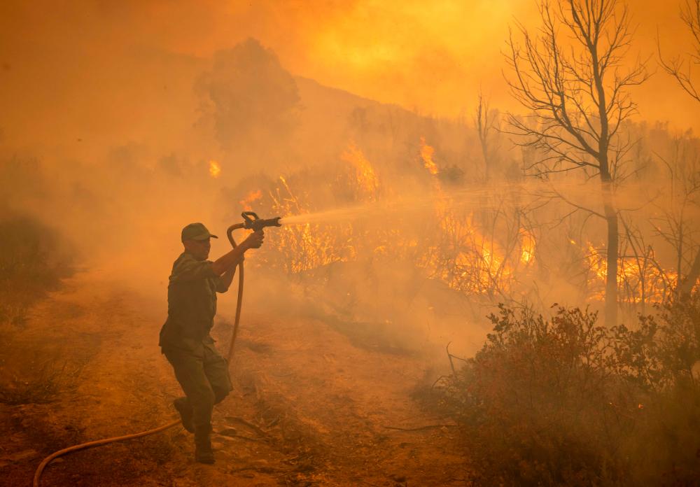 A Moroccan soldier sprays water from a hose on a forest fire near the Moroccan city of Ksar el-Kebir in the Larache region, on July 15, 2022. AFPpix
