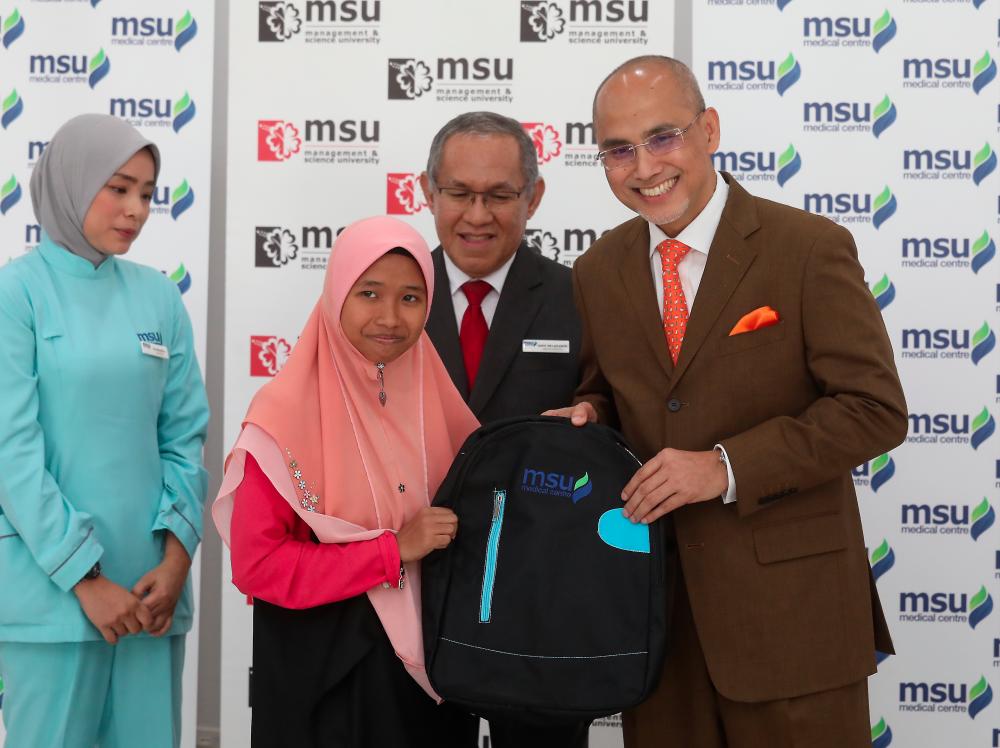 Mohd Shukri with a child who received a pair of prescription glasses. SUNPIX by MASRY CHE ANI