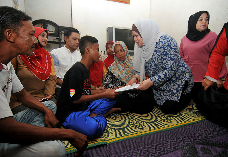 Rural and Regional Development Minister Datuk Seri Rina Harun (2nd R) presents Muhammad Aiman Afiq Mohd Basri’ (3rd L) with the letter of offer to the Transkrian MRSM, at his home, on Dec 31, 2018. — Bernama