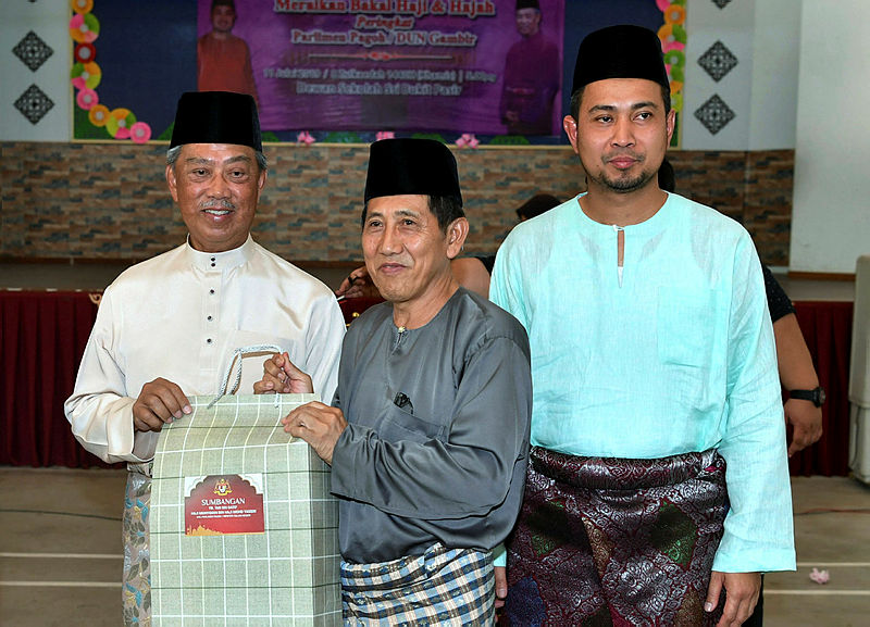 Home Minister Tan Sri Muhyiddin Yassin (L) and Johor Mentri Besar Datuk Dr Sahruddin Jamal (R), pose for a picture with a fellow haj pilgrim, Atiman Kadar (C), on July 11, 2019. — Bernama