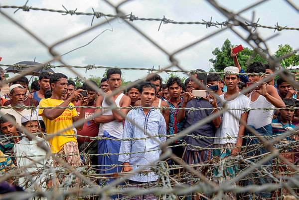 Rohingya refugees gather near the fence in the “no man’s land” zone between Myanmar and Bangladesh border as seen from Maungdaw, Rakhine state during a government-organized visit for journalists on Aug 24, 2018 — AFP