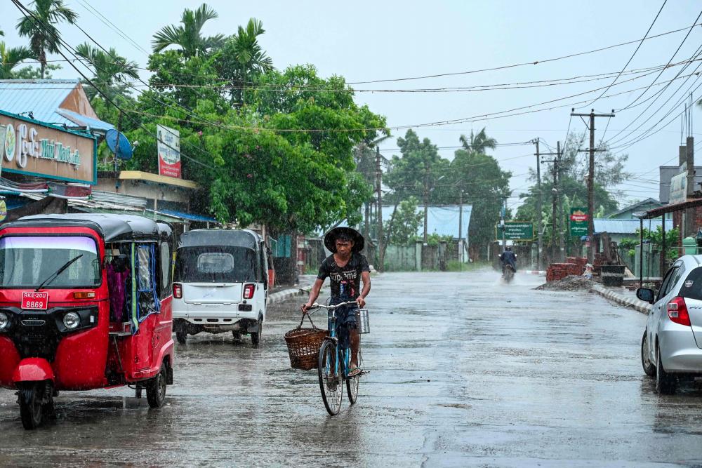 A man rides his a bicycle in an almost empty street in Kyauktaw in Myanmar’s Rakhine state on May 14, 2023, ahead of the expected landfall of Cyclone Mocha. - AFPPIX