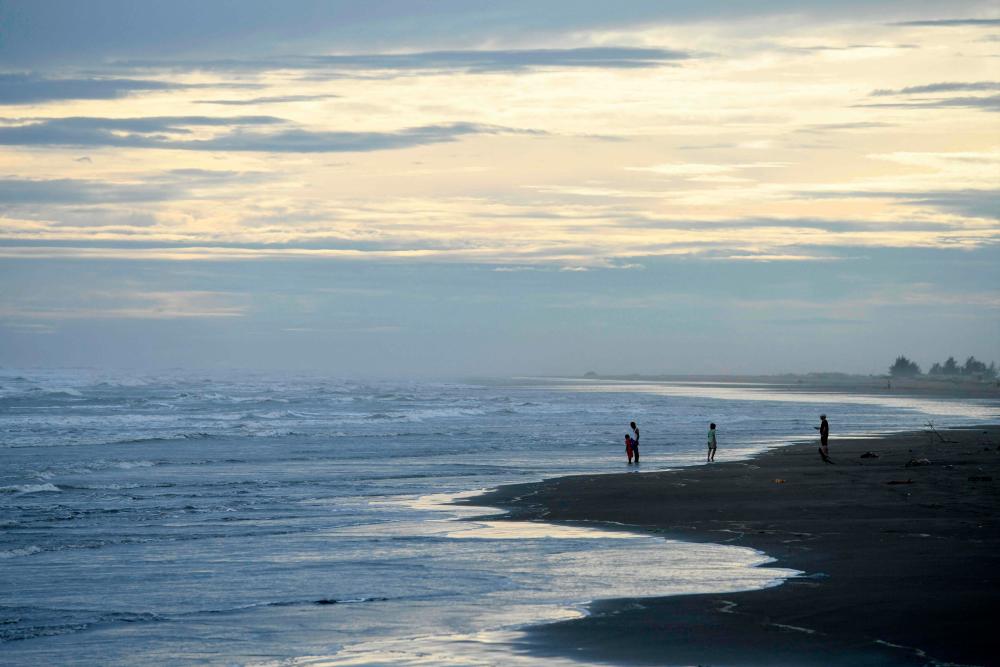 People stand by the sea in Sittwe in Myanmar’s Rakhine state on May 12, 2023, ahead of the expected arrival of Cyclone Mocha. AFPPIX