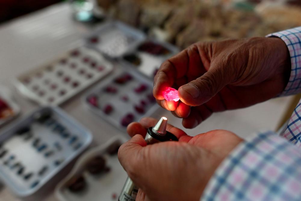 This photo taken on May 17, 2019 shows a buyer inspecting a ruby at the gems market in Mogok town, north of Mandalay. Burrowing deep underground, thousands of informal miners risk their lives to find gleaming red gems as a law change spurs opportunity in Myanmar's land of rubies. — AFP