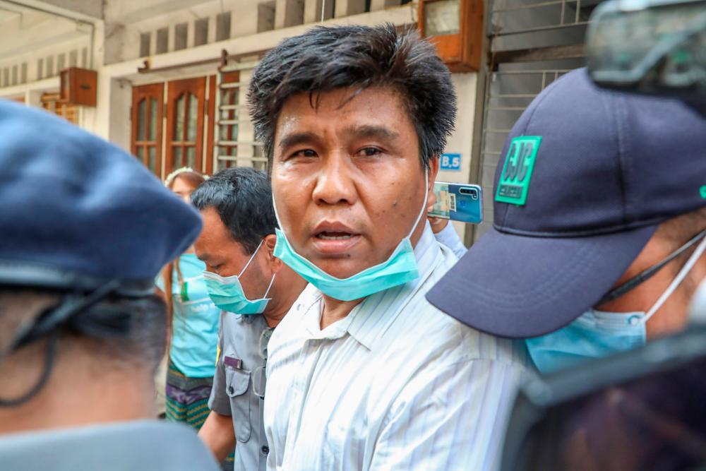 Voice of Myanmar (VOM) editor-in-chief Nay Myo Lin is escorted from his home by police to court in Mandalay on March 31, 2020. - AFP