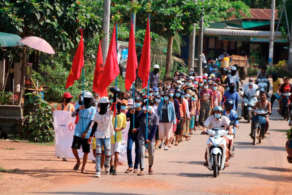 This handout photo taken and released by Dawei Watch on April 10, 2021 shows protesters holding flags as they march in a demonstration against the military coup in Launglone township in Myanmar’s Dawei district. - AFP