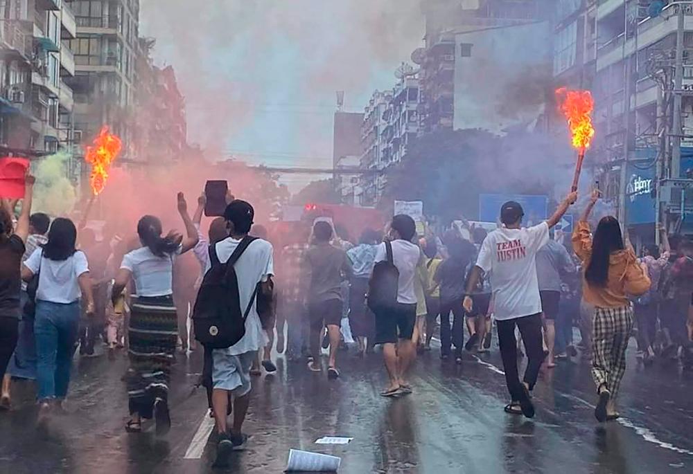 This photo taken and received courtesy of an anonymous source via Facebook on June 26, 2021 shows protesters marching with flaming torches as they take part in a demonstration against the military coup in Yangon. – AFP