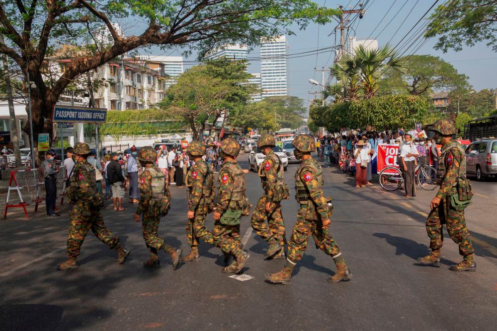 Soldiers cross a street as people gather to protest against the military coup, in Yangon, Myanmar, February 15, 2021. — Reuters/Stringer