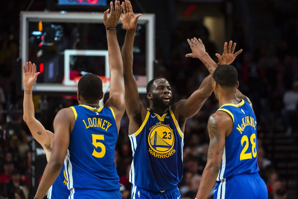 Golden State Warriors forward Draymond Green (23) gives high-fives to teammates center Kevon Looney (5) and forward Alfonzo McKinnie (28) during the second half in game three of the Western conference finals of the 2019 NBA Playoffs at Moda Center. - Reuters