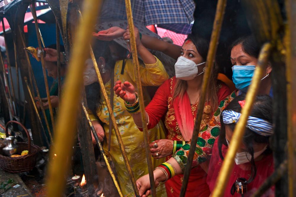 Hindu devotees hold up offerings in honour to the Hindu Lord Shiva during Shravan festivities at the Shiva temple in Kathmandu on July 20, 2020. According to the Nepali calendar, Shravan is considered the holiest month of the year with each Monday of the month known as Shravan Somvar, when worshippers offer prayers for a happy and prosperous life. / AFP / PRAKASH MATHEMA