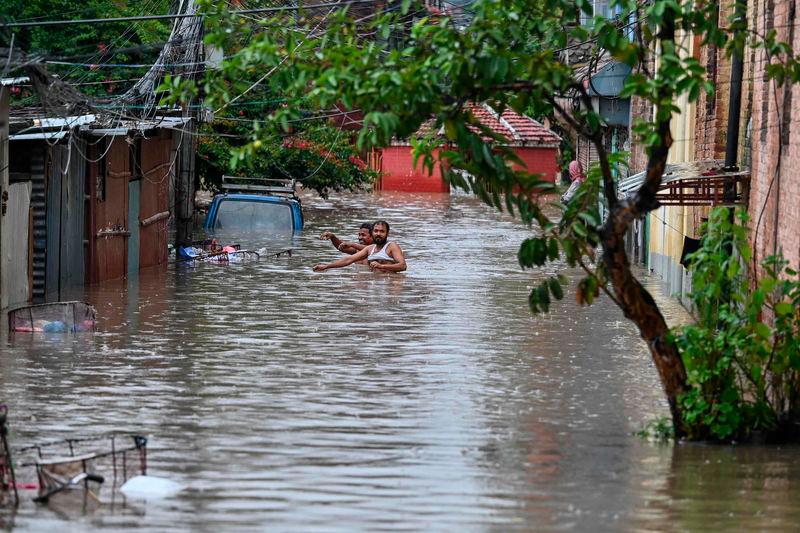 Local residents wade through flood waters after the Bishnumati River overflowed following heavy rainfall in Kathmandu - AFPpix