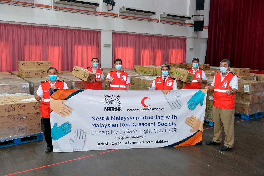 Representatives from the Malaysian Red Crescent Society receiving cash and product donations from Nestlé Malaysia for immediate COVID-19 pandemic relief efforts.