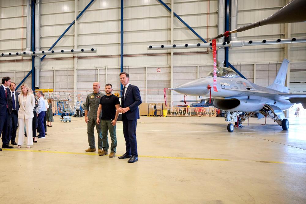 This photograph taken and released by the Ukrainian Presidential Press Service on August 20, 2023, shows Ukraine’s President Volodymyr Zelensky (2nd-R) and Dutch Prime Minister Mark Rutte (R) standing next to a F-16 fighter jet in the hangar at the Eindhoven Military Air Base in Eindhoven. AFPPIX