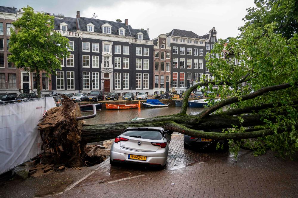 A storm damaged tree lies on a vehicle on the Keizersgracht in the centre of Amsterdam on July 5, 2023, after winds of ‘ Storm Poly’ struck north Holland where a ‘code red’ was issued as an extreme weather warning/AFPPix