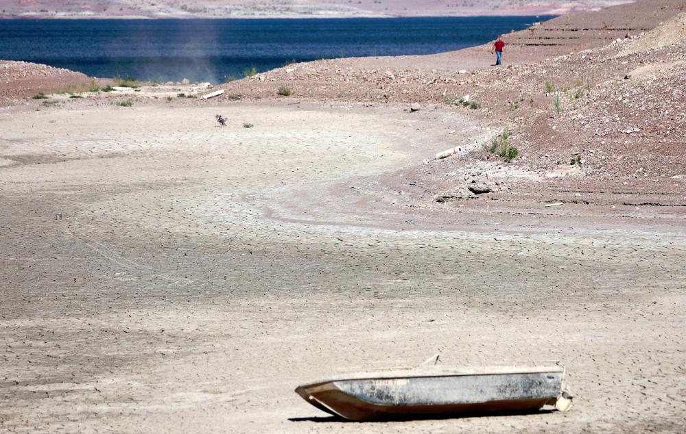 A person walks near a formally sunken boat resting on a section of dry lakebed along drought-stricken. - AFPpix