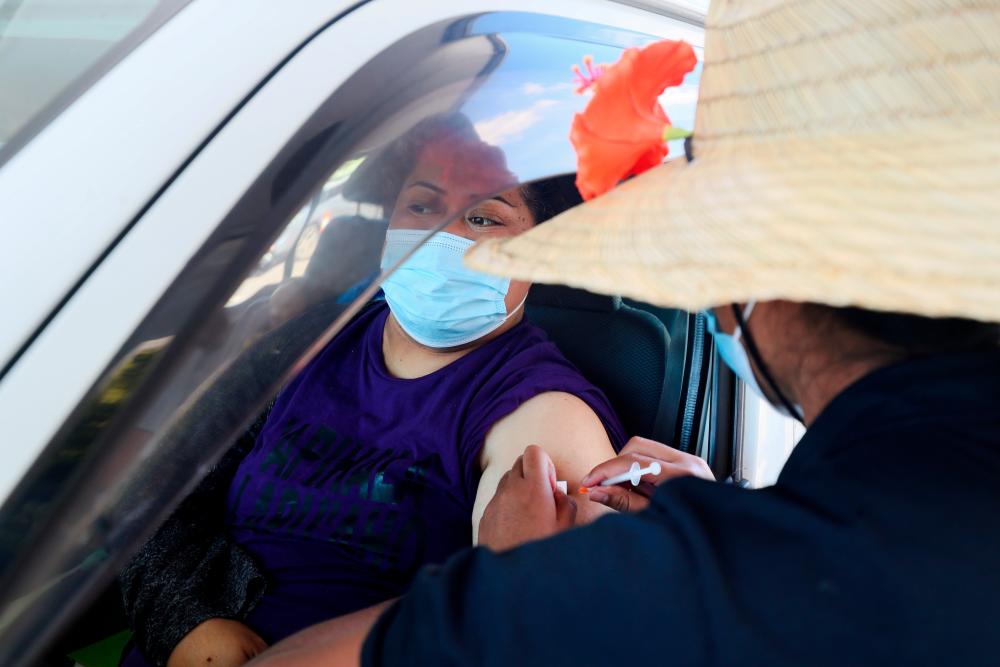 FILE PHOTO: A member of the public receives a Pfizer vaccine at a drive-through coronavirus disease (Covid-19) vaccination clinic in Otara during a single-day vaccination drive, aimed at significantly increasing the percentage of vaccinated people in the country, in Auckland, New Zealand, October 16, 2021. REUTERSpix