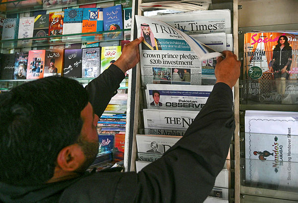 A Pakistani man looks at morning newspapers with front-page-coverage of Saudi Arabian Crown Prince Mohammed bin Salman at a roadside stall in Islamabad — AFP