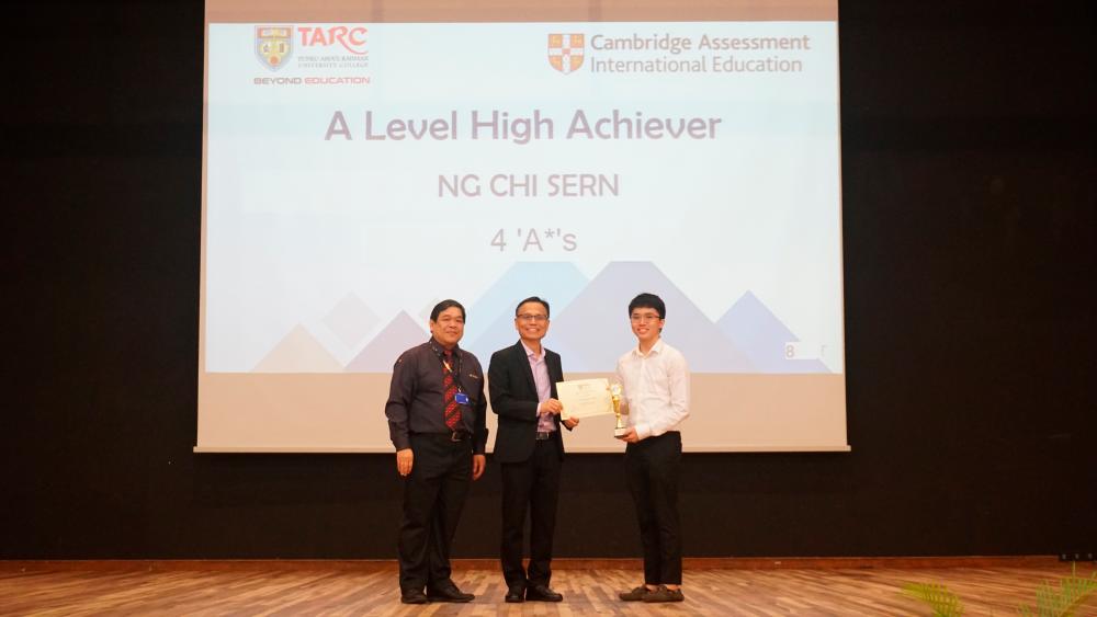 Ng receiving the Centre for Pre-University Studies (CPUS) A Levels High Achievers Award certificate and trophy from Lee and (on far left) Head of CPUS Yeoh Hock Seng.